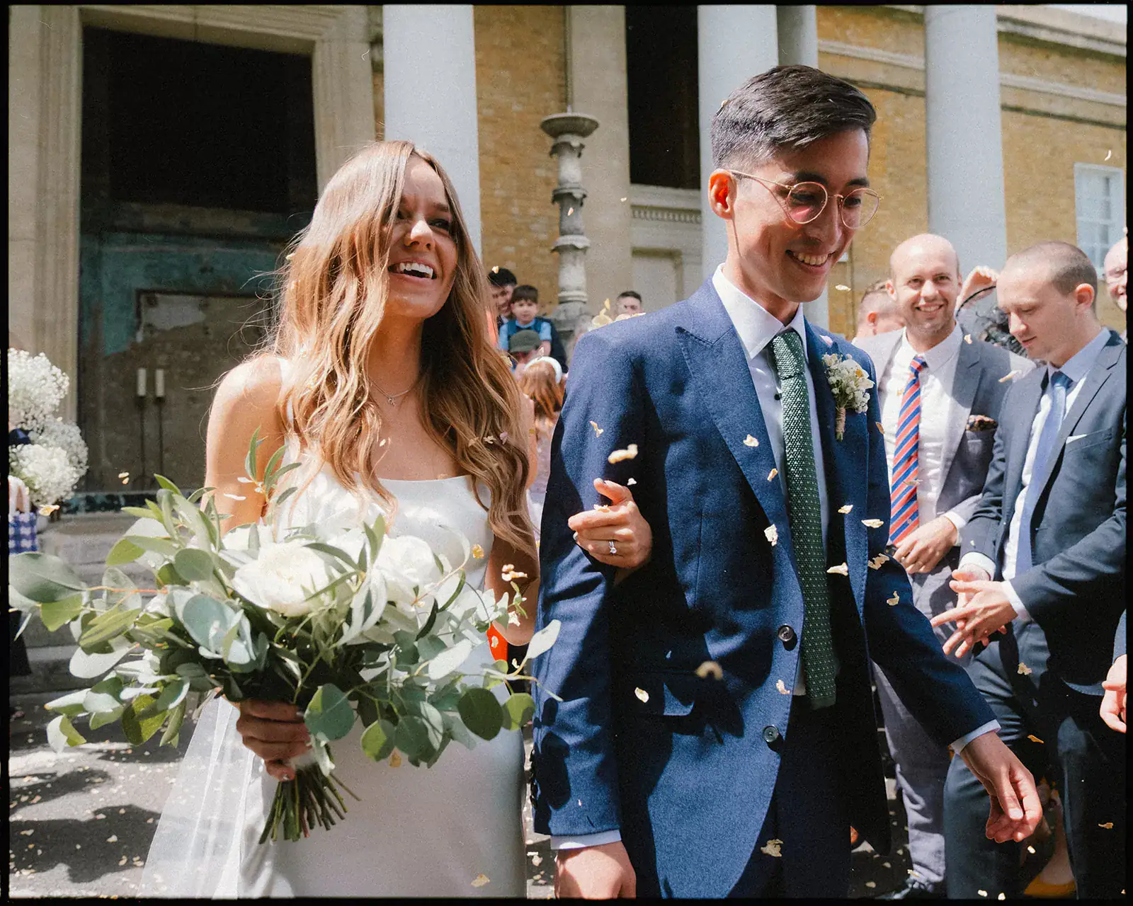 bride and groom walking through confetti arm in arm
