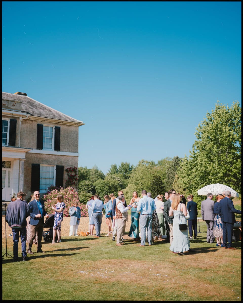 Guests mingling on the lawn during drinks reception at Preston Court wedding venue in Kent.