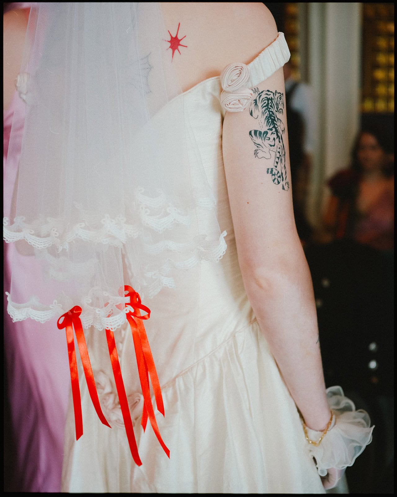Close-up of a bride’s vintage dress and veil with custom red ribbons while getting ready at The Grand Brighton before her Brighton Town Hall wedding.