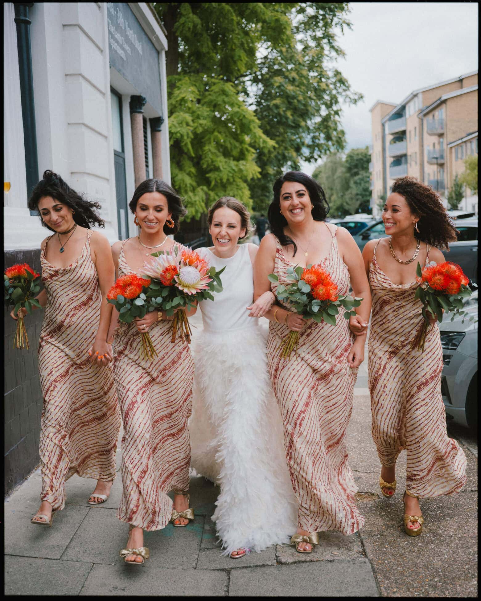 bride with bridesmaids owning it and walking down north london street with bouquets