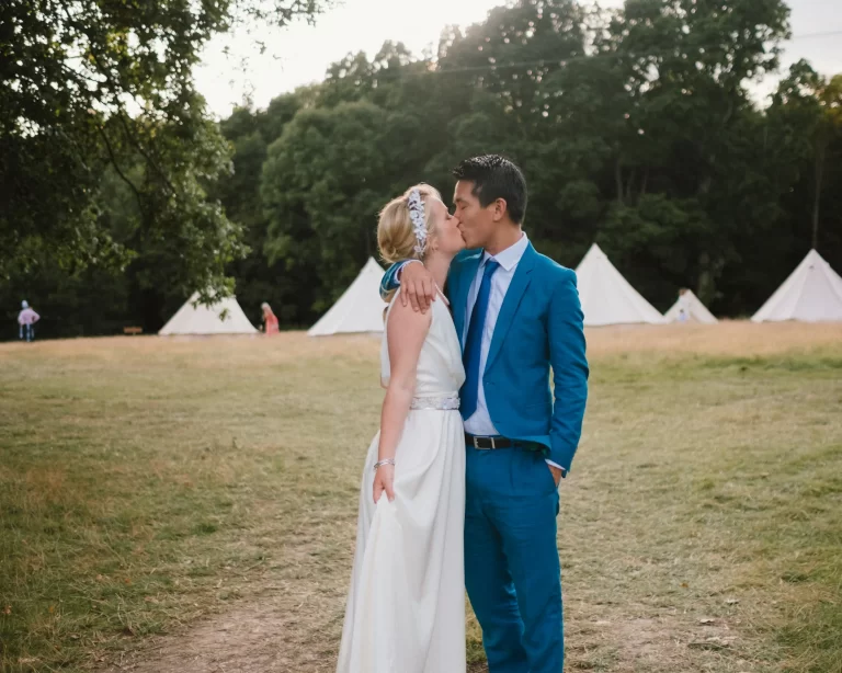 couple kissing in front of tents at exclusive woodland wedding venue paper mill kent