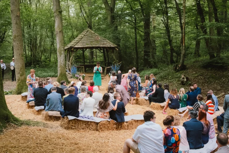 guests sat before ceremony in the woods at exclusive woodland wedding venue paper mill hawkhurst kent