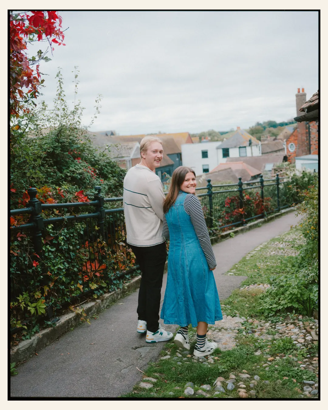 american couple walking down narrow path in the ancient town of rye for their engagement shoot ahead of their destination wedding
