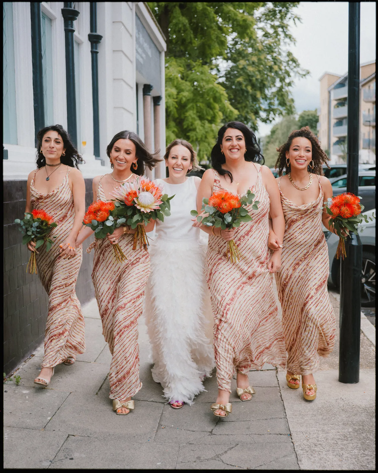 The Depot Wedding Photographer London - Bridesmaids in arms walking down street 