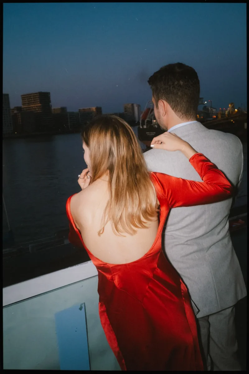 greenwich yacht club wedding photographer london - couple looking over the thames at night in red dress