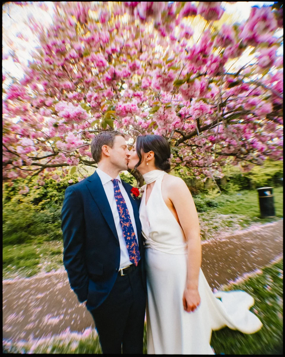 camberwell arms wedding - bride groom kissing warped lens under cherry blossom