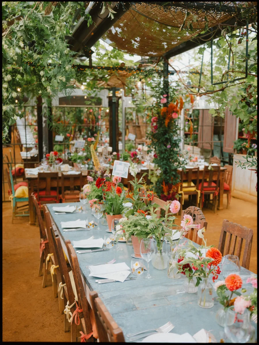 Wedding table of dahlias and pink blooms in vases under the glasshouse at Petersham Nurseries