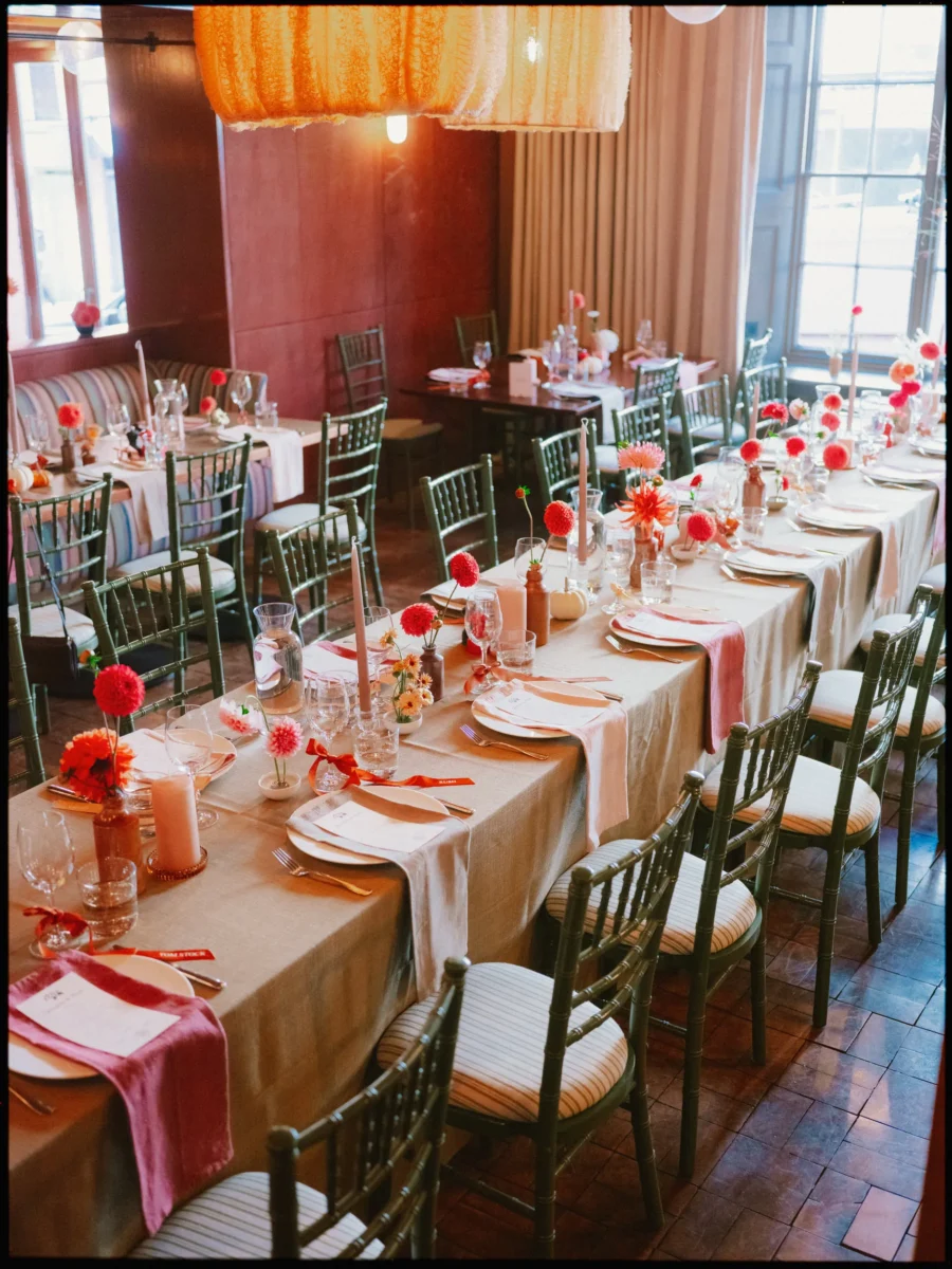 Long wedding table set with red dahlias and rose napkins under glowing orange lampshades in The George restaurant