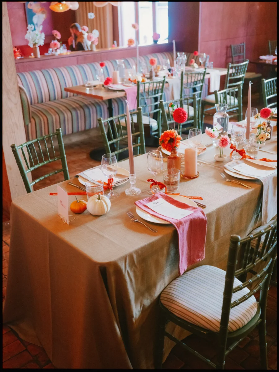 Dinner table with pink napkins, taper candles and mini pumpkins beside a striped banquette in The George restaurant