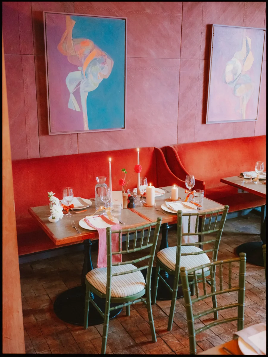 Candlelit table with pink napkins and posies by a red velvet banquette at The George in Rye