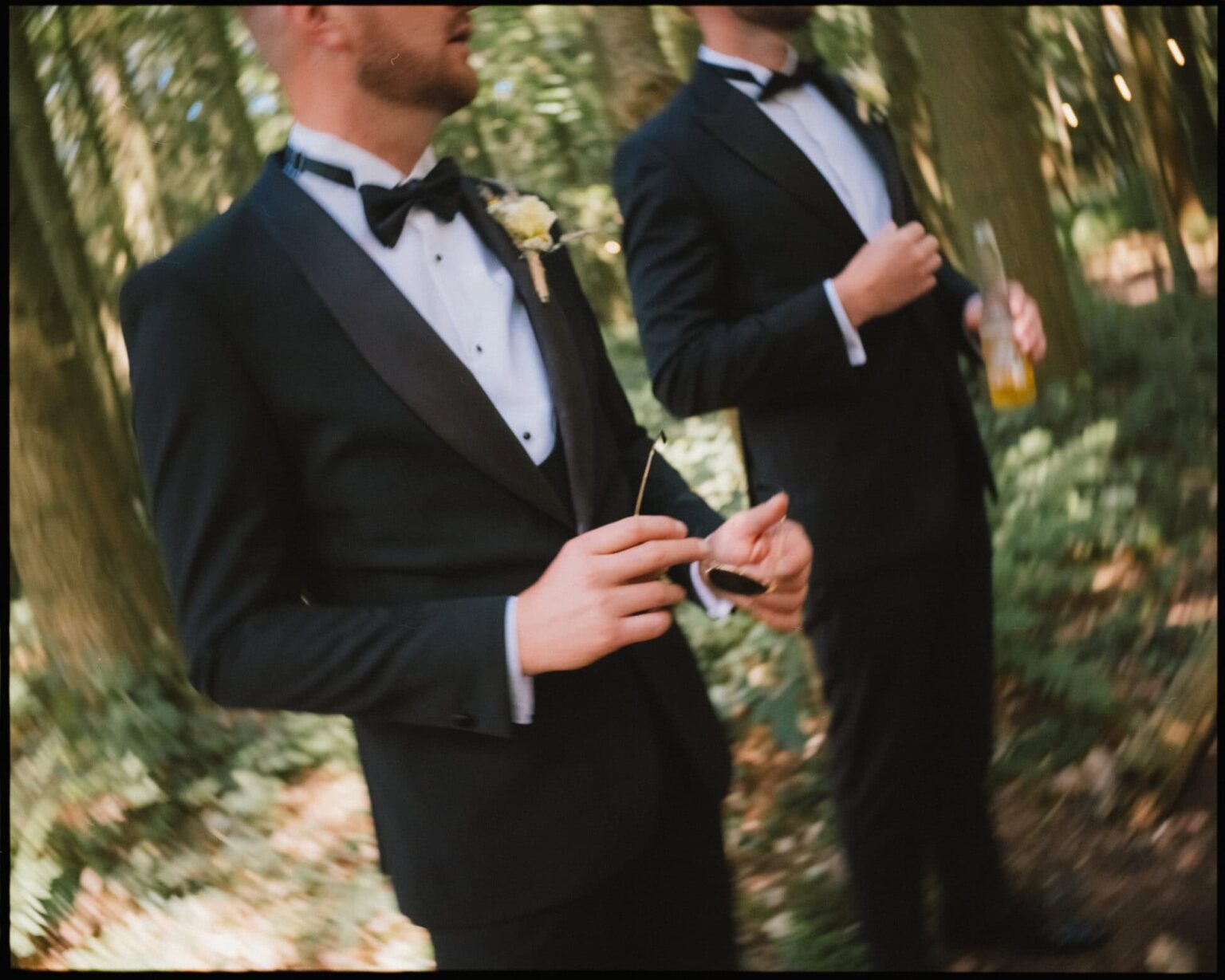 A candid moment before the ceremony — groomsmen in tuxedos waiting among the trees at Longton Wood. The motion blur adds a sense of anticipation and drama. Groomsmen in black tuxedos waiting in the woods before the wedding ceremony at Longton Wood.