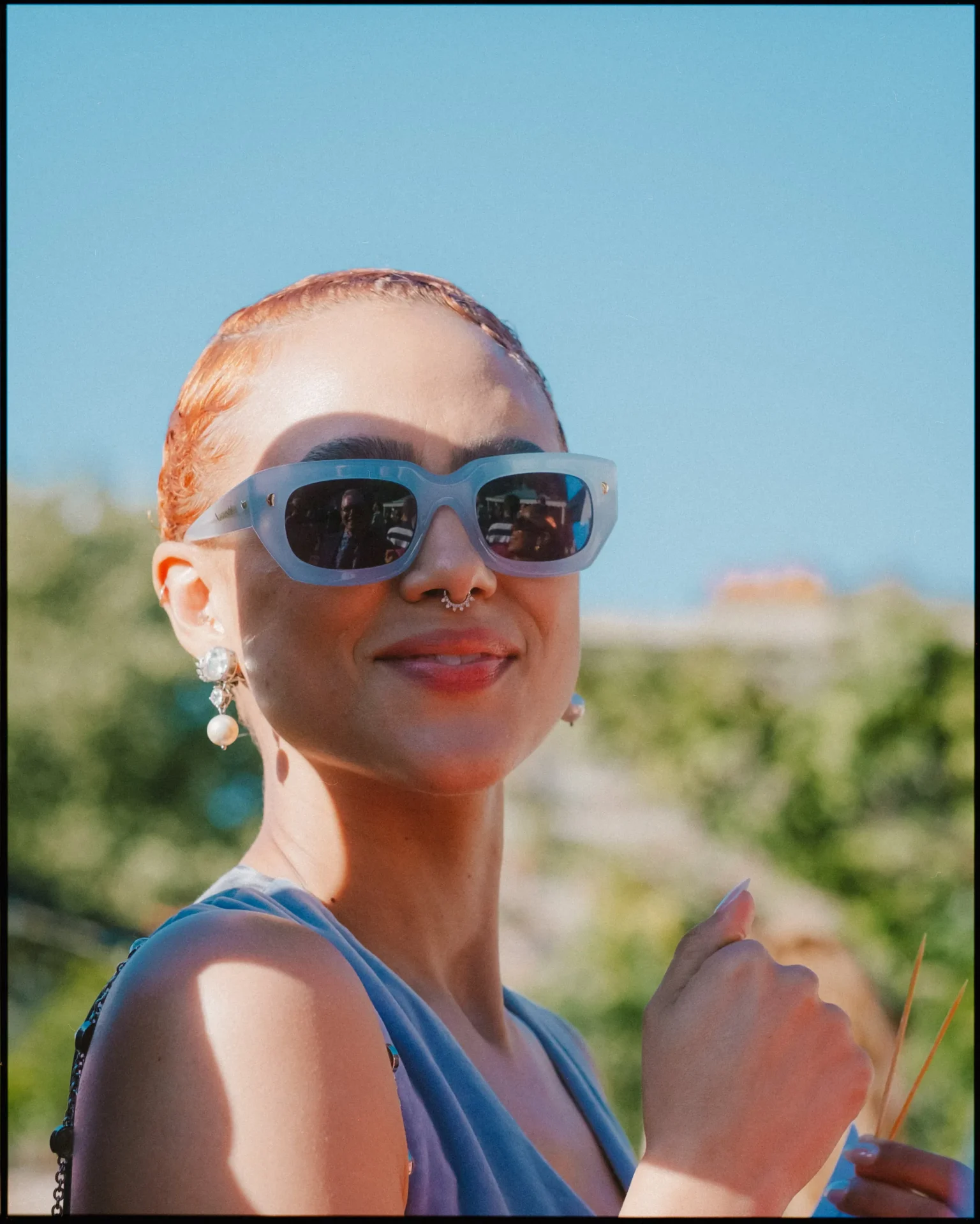 A woman wearing sunglasses and smiling.